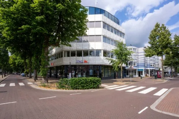 Wit kantoorpand op de hoek van de 1e Hogeweg met op de begane grond een ING-bankfiliaal.